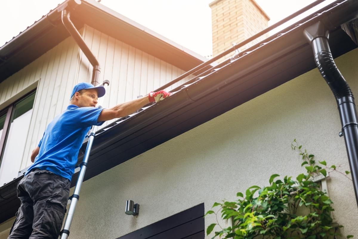 image showing person climbing roof to install gutter guards