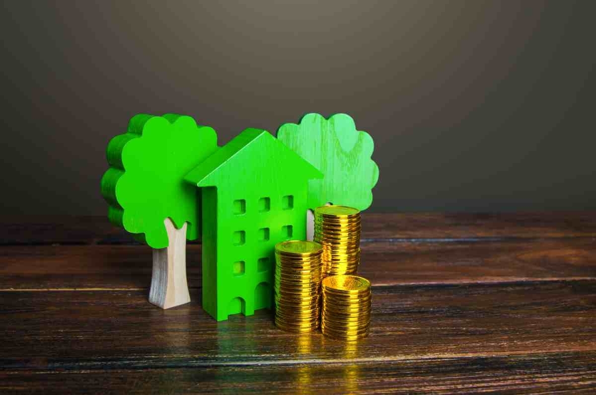 image showing coins piled up next to green house figure and fake trees