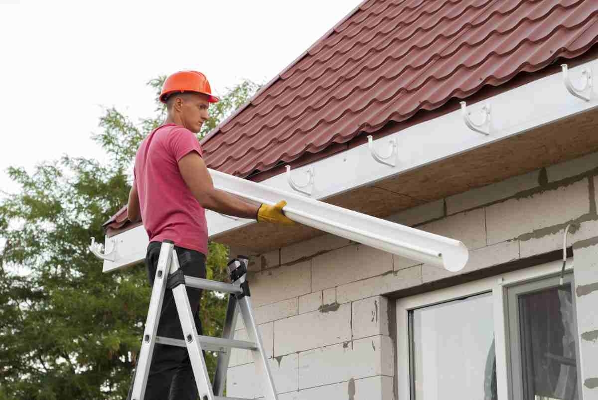 image of professional removing gutters from home before installing gutter guards