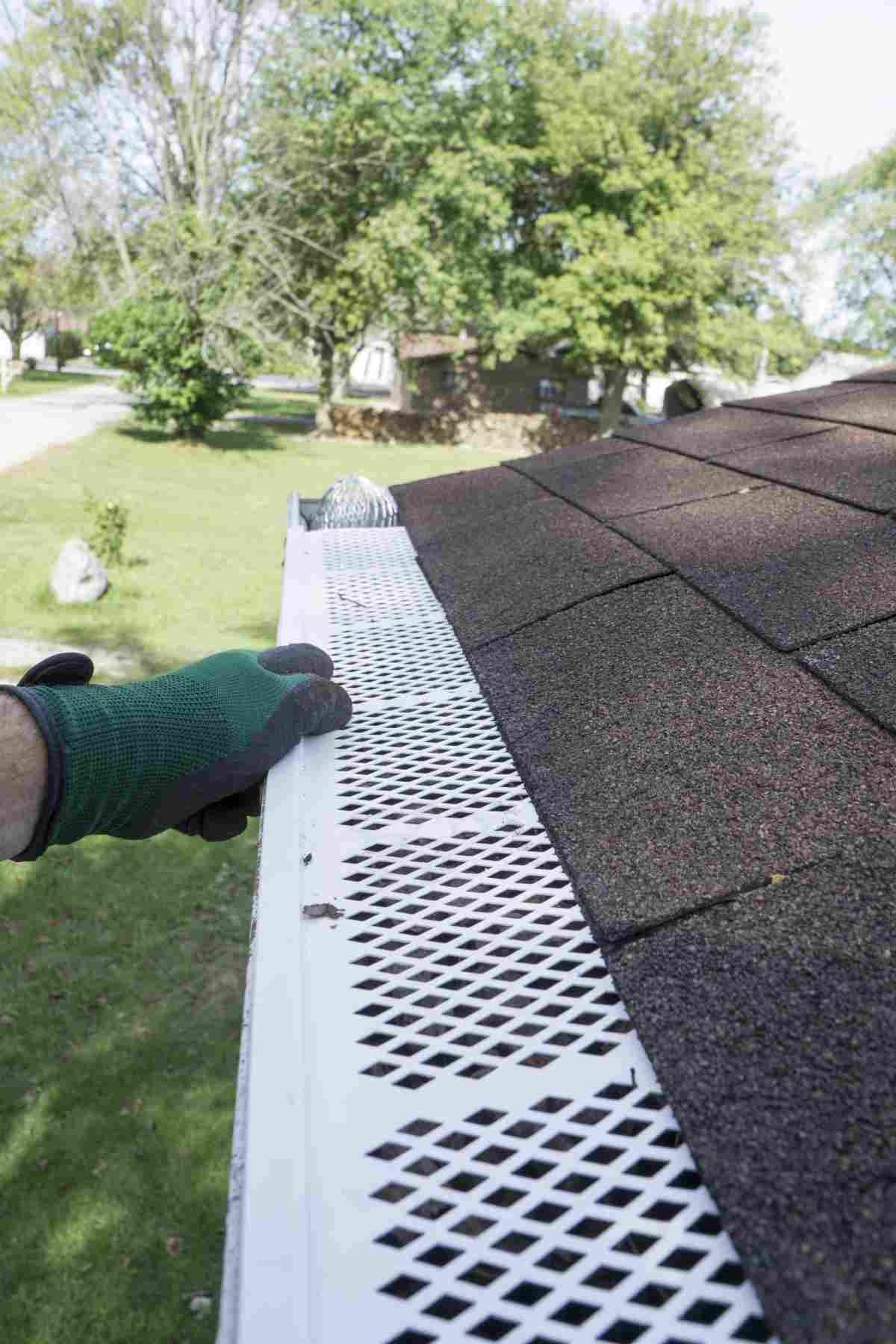 image showing hand covered by gloved installing gutter guard