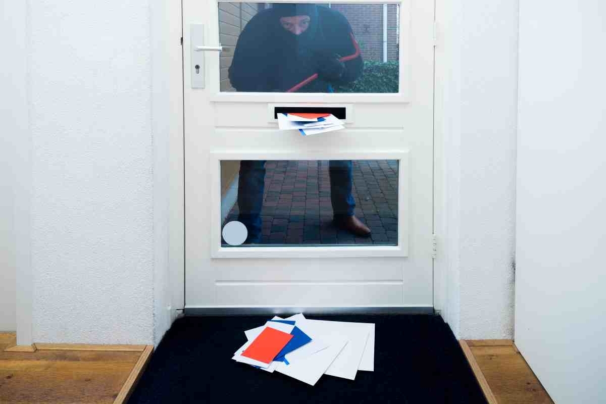 image showing a burglar trying to break into a home with an overflowed mail box