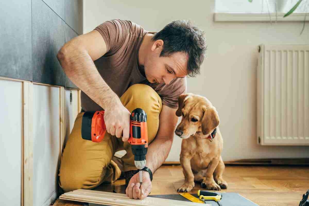 image showing a homeowner attempting a DIY project with his dog next to him