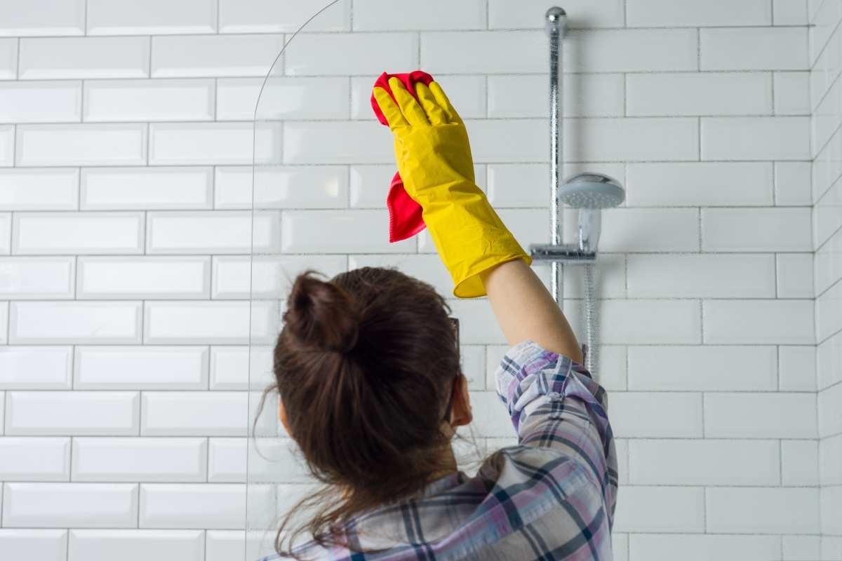 image showing woman cleaning the walls of a bathroom