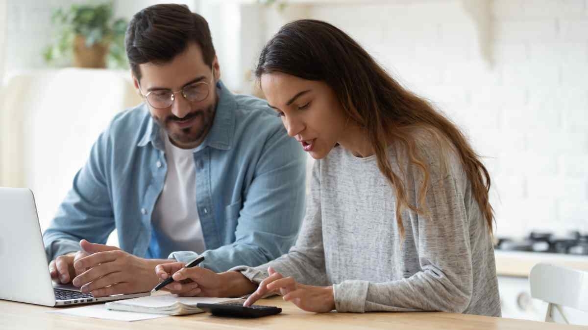 image showing young couple looking at a calculator and papers on the table in the kitchen