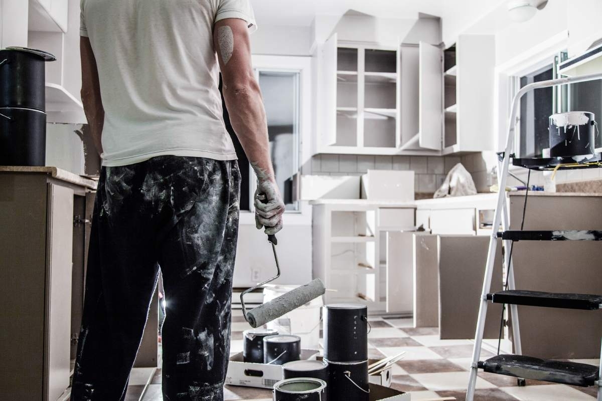 image showing a man in a kitchen holding a paint roller in his hand