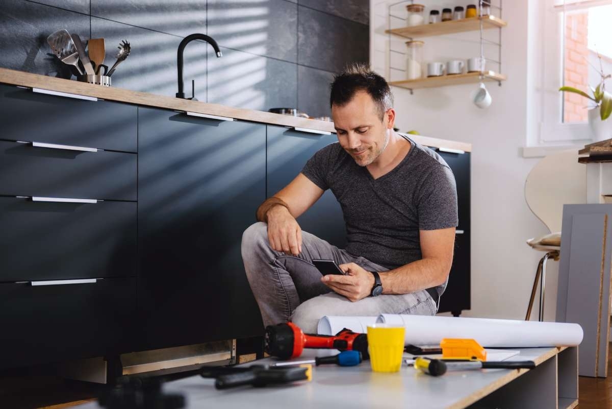 image showing a man in a kitchen with different tools for a remodel