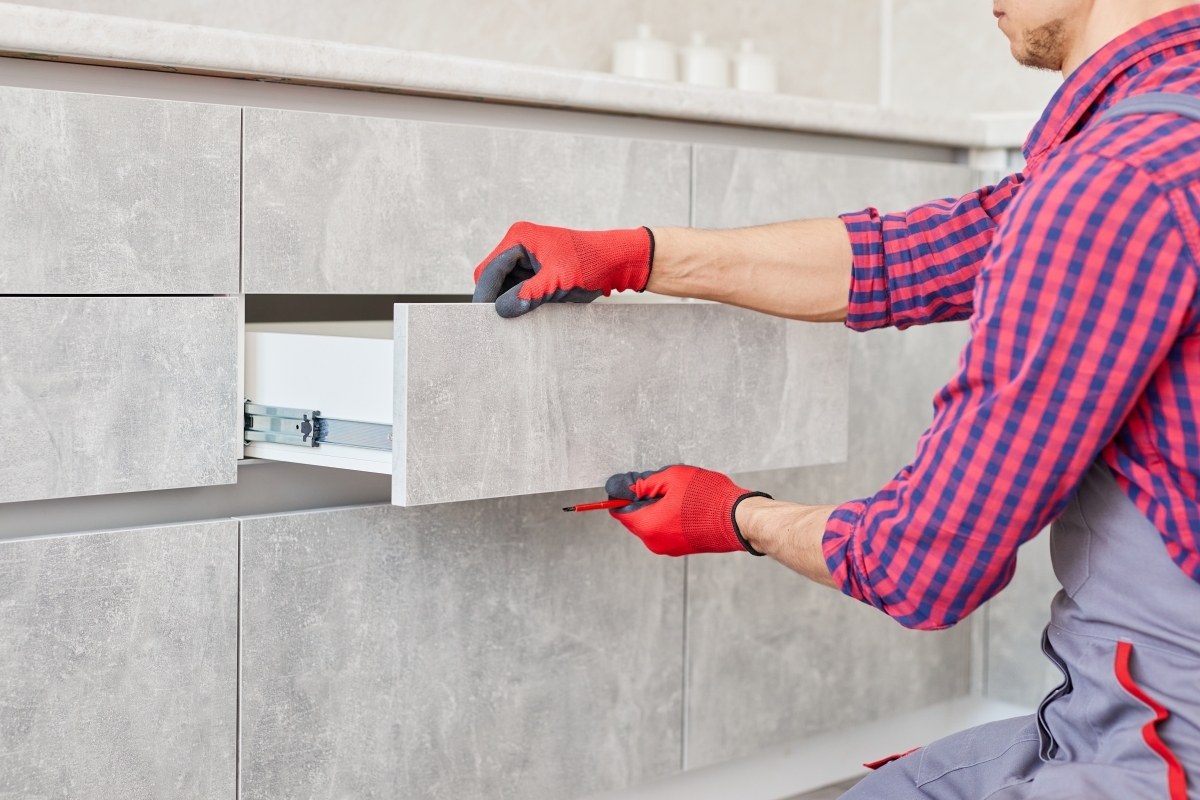 image showing a repairman installing kitchen cabinets