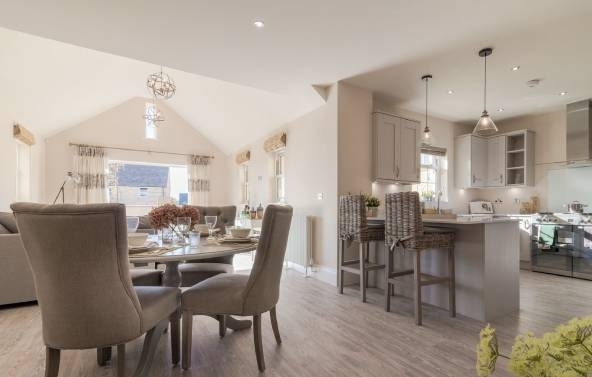 Dinining room, chairs, and integrated kitchen on the right,  in light brown tones.