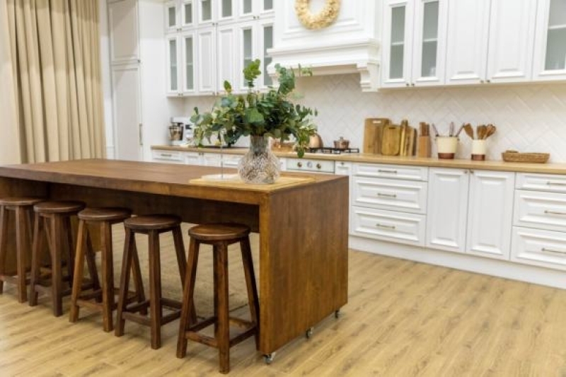 Modern kitchen featuring white cabinets, a warm wood island, and tall barstool seating.