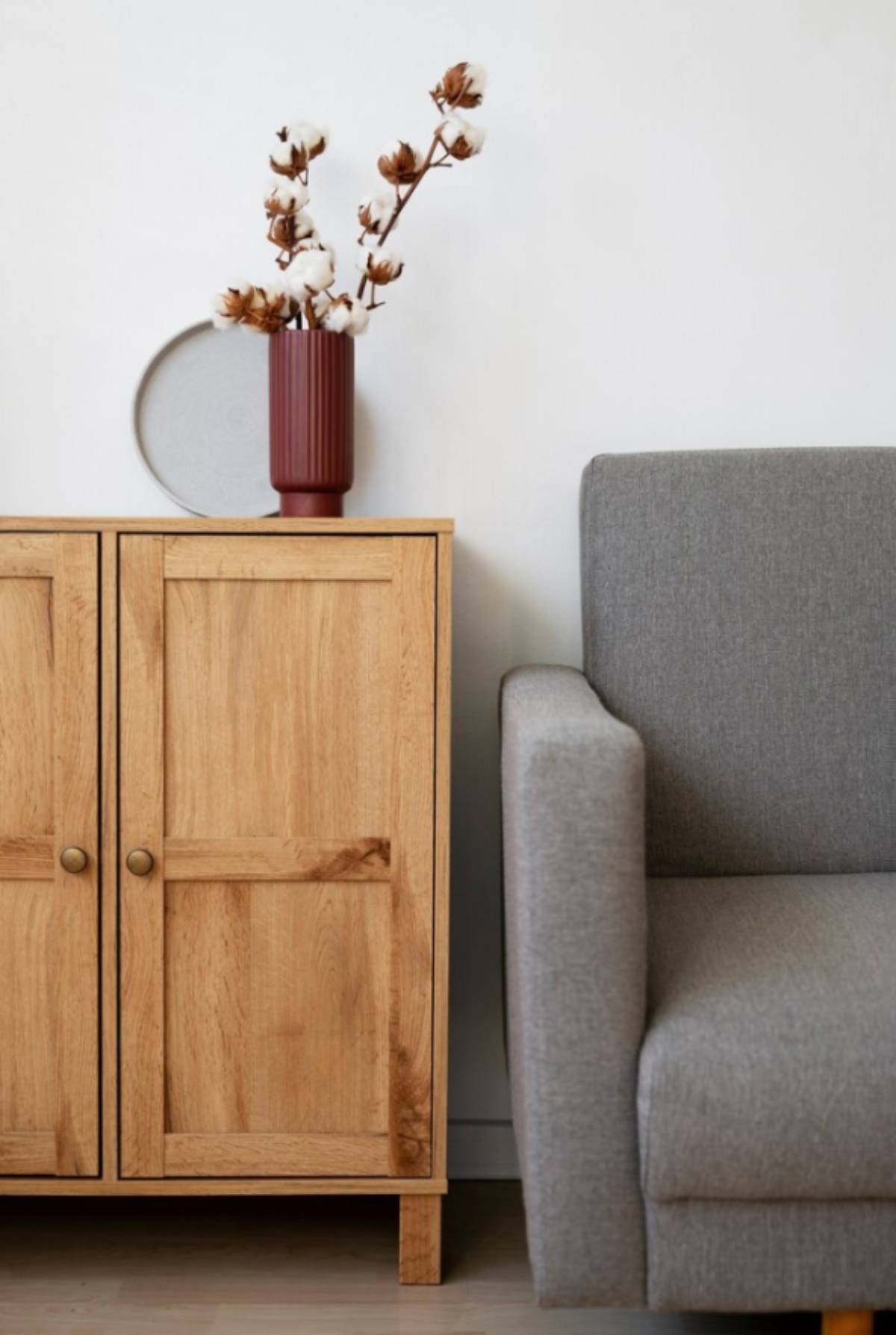 wood cabinet next a grey couch